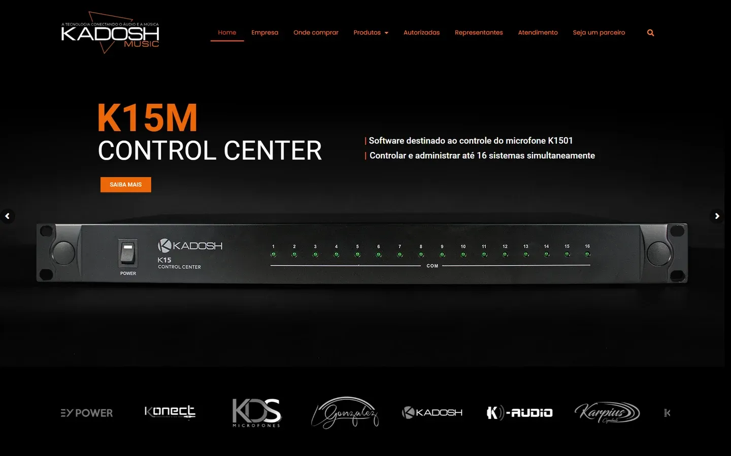 Home da Kadosh Music na versão de 2022, com o menu em laranja sobre fundo preto, o destaque K15M Control Center, software que controla até 16 sistemas do microfone K1501, a foto do aparelho de rack e a faixa com os logotipos das marcas.